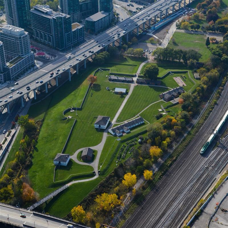 An overhead shot of a green area next to a highway and train tracks. 