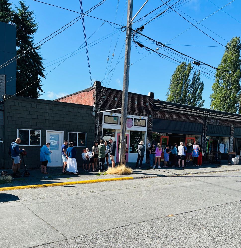 Brick building with long line of people waiting at our neighborhood bakery.