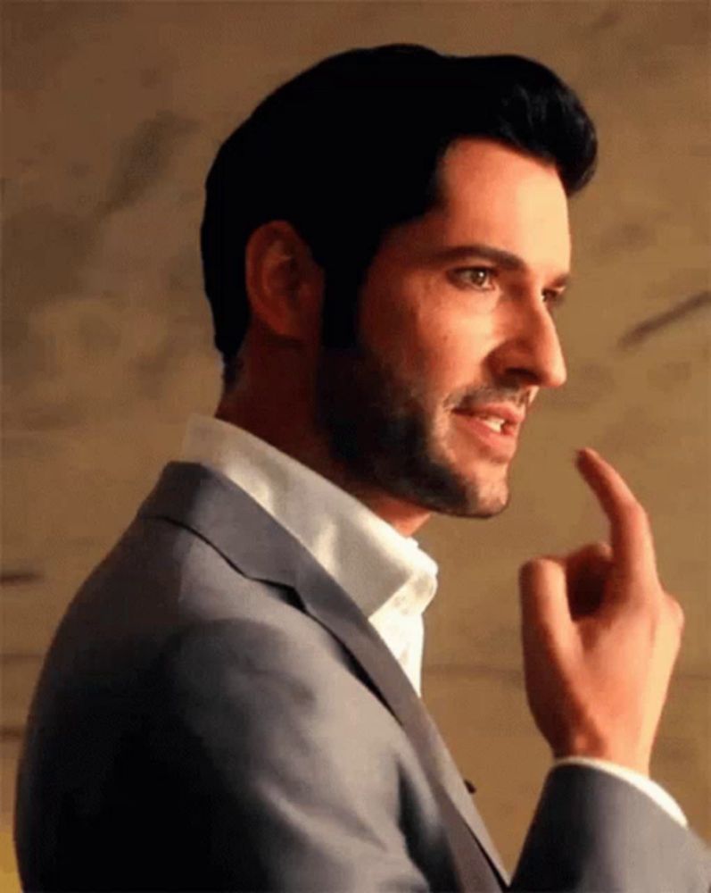 a man with a beard wearing a suit and white shirt is pointing his finger