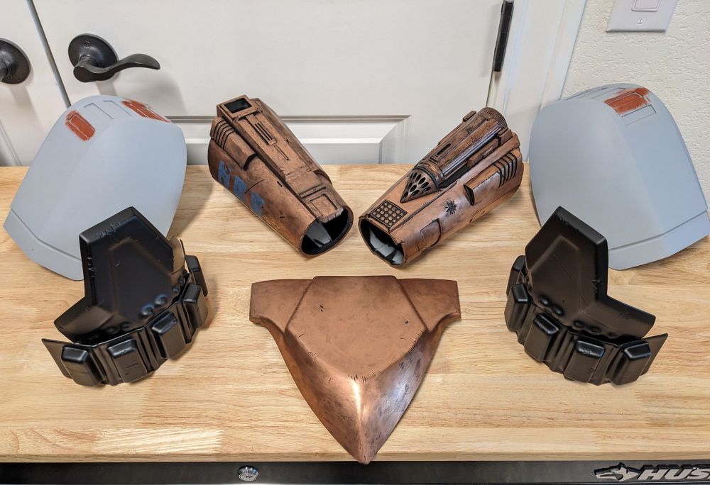 Mandalorian armor costume pieces in varying stages of progress. Bracers, cod plate, knee plates, and shoulder plates.