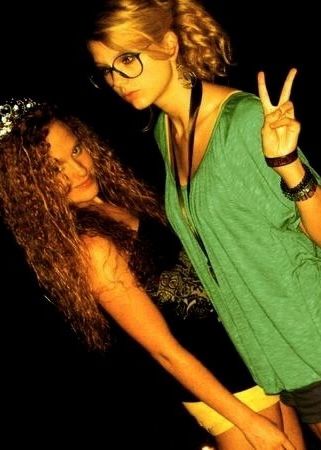 Taylor and Abigail when they were younger. Taylor is wearing big glasses and giving the peace sign, while Abigail looks at the camera and smiles. 