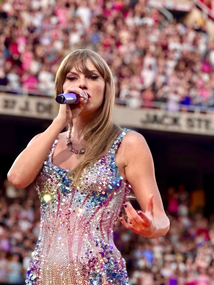 Taylor Swift on stage at the eras tour during the lover set. She’s wearing the blue and pink bodysuit. 