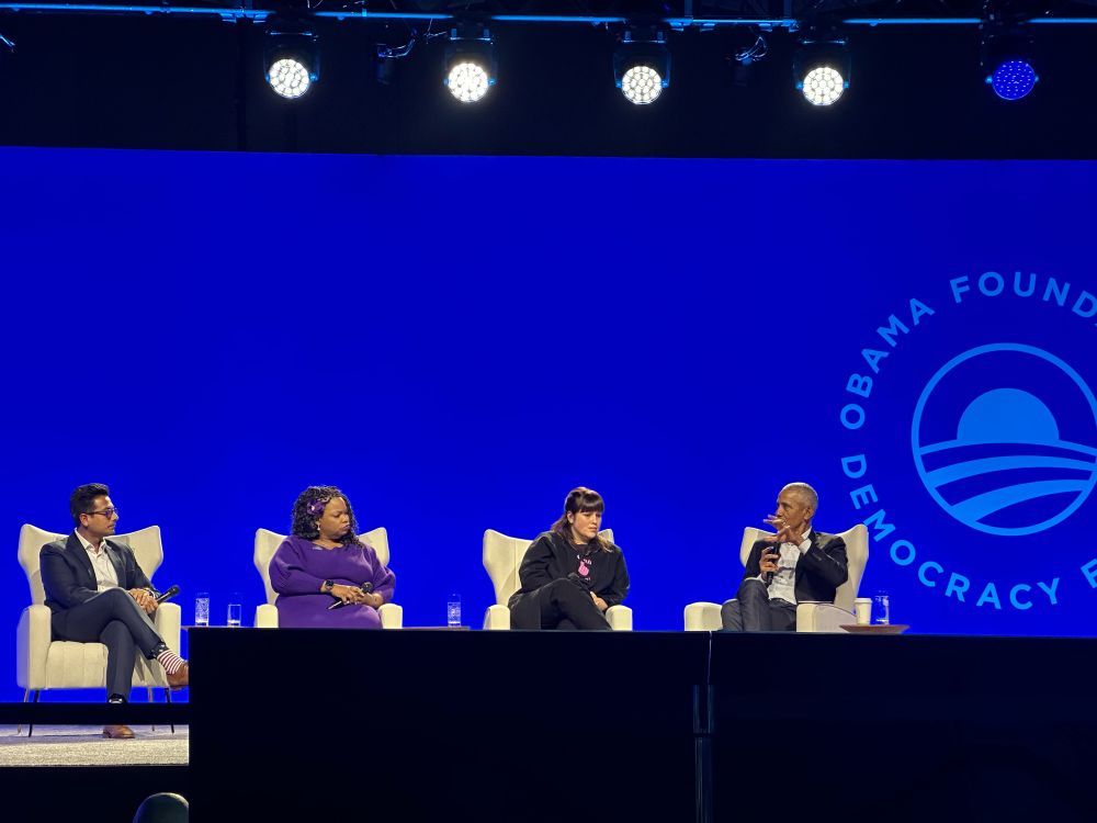 President Obama seated with 3 panelists - one man and two women who he is interviewing. 