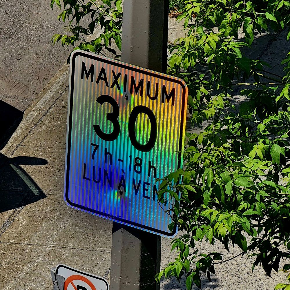 Slow speed sign in Montreal that relects the light with rainbow colours.
