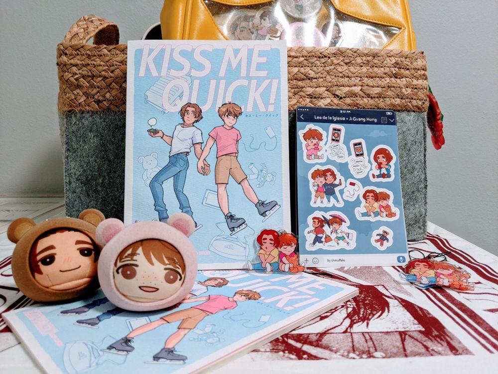 Display of "Kiss Me Quick" leoji doujinshi, sticker sheets, and acrylic charms, joined by Leo and Guang Hong manju toys