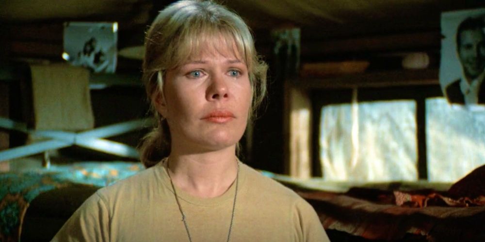 Loretta Swit as Major Margaret "Hot Lips" Houlihan in MASH. She's in the nurses' barracks (there's a bunkbed and some B&W pinup photos of men in the background), wearing a khaki T-shirt with a thin chain (probably her dog tags) and is teary-eyed. The shot is from the 5th season episode "Nurses".