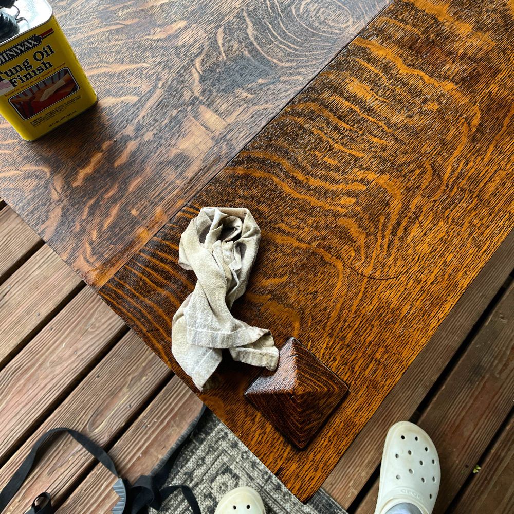 A rag with tung oil on top of richly flaked 100 year old oak that has just been oiled