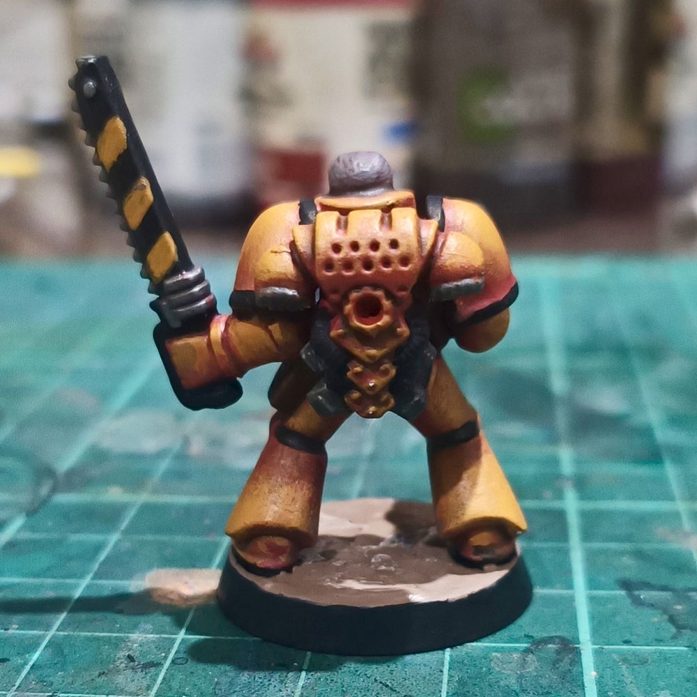Rear view. The hazard stripes on the chainsword are visible from this angle.