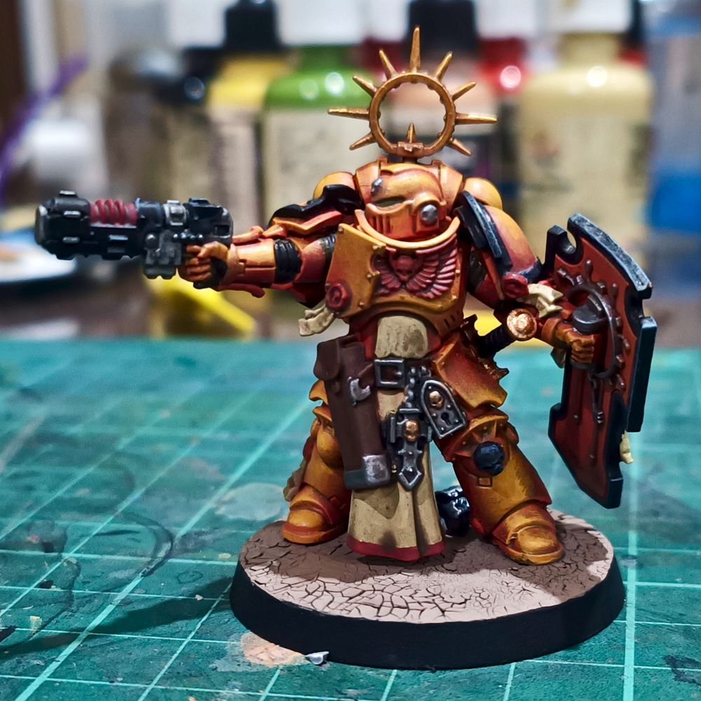 Painted model of an Imperial Fists bladeguard sergeant aiming a neo-volkite pistol with one hand while holding his shield in the other