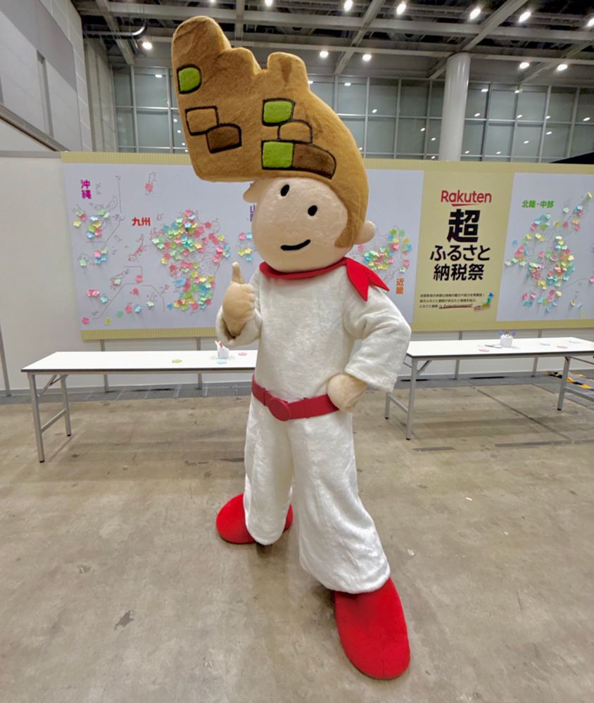 A mascot in a white jump suit with a stonemasonry pompadour haircut gives a thumbs-up.