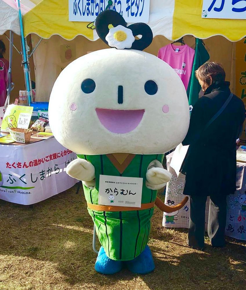 A caterpillar mascot with the face of a snowman and a flower on his head