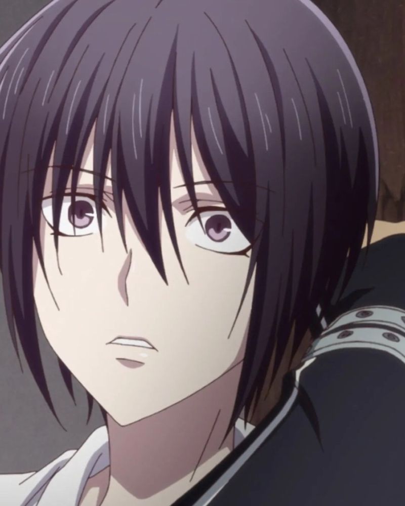 Close-up of Akito Sohma from Fruits Basket. Akito has dark hair with bangs partially covering their face and light violet eyes. Their expression is tense and slightly parted lips suggest surprise or emotional vulnerability. The lighting and angle emphasize a moment of intensity or revelation.