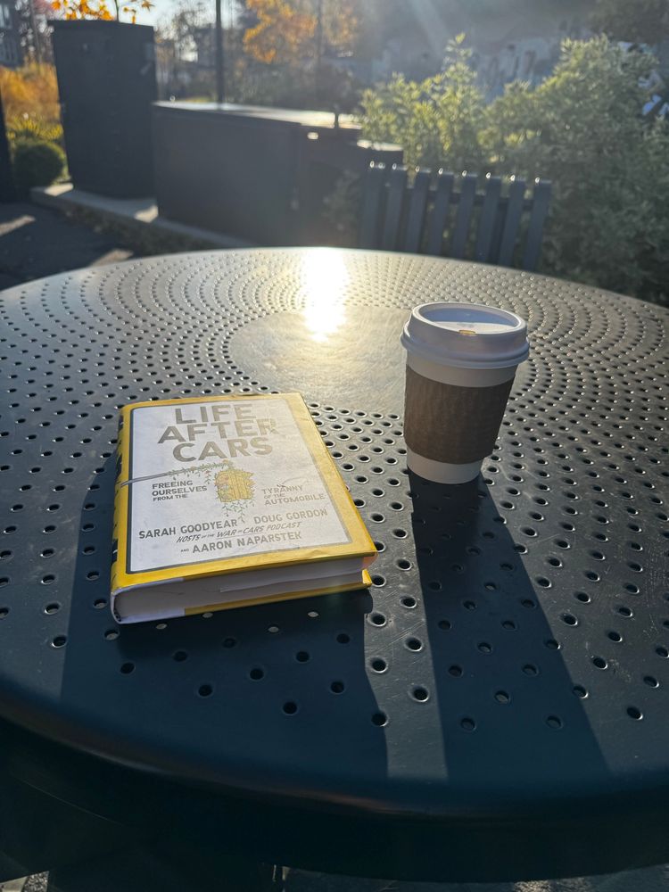 The book life after cars and a coffee cup on an outdoor metal table