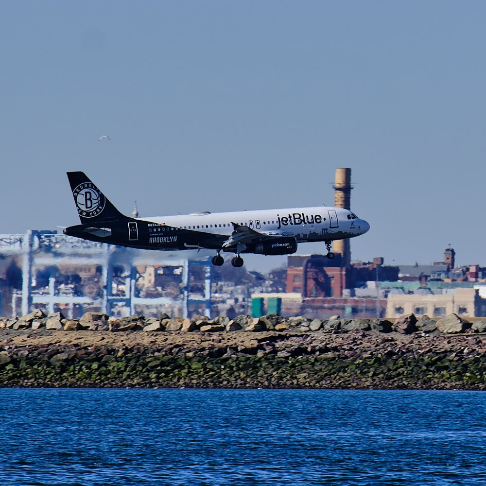 Close up of a white and black airplane about to touch down at Logan airport.