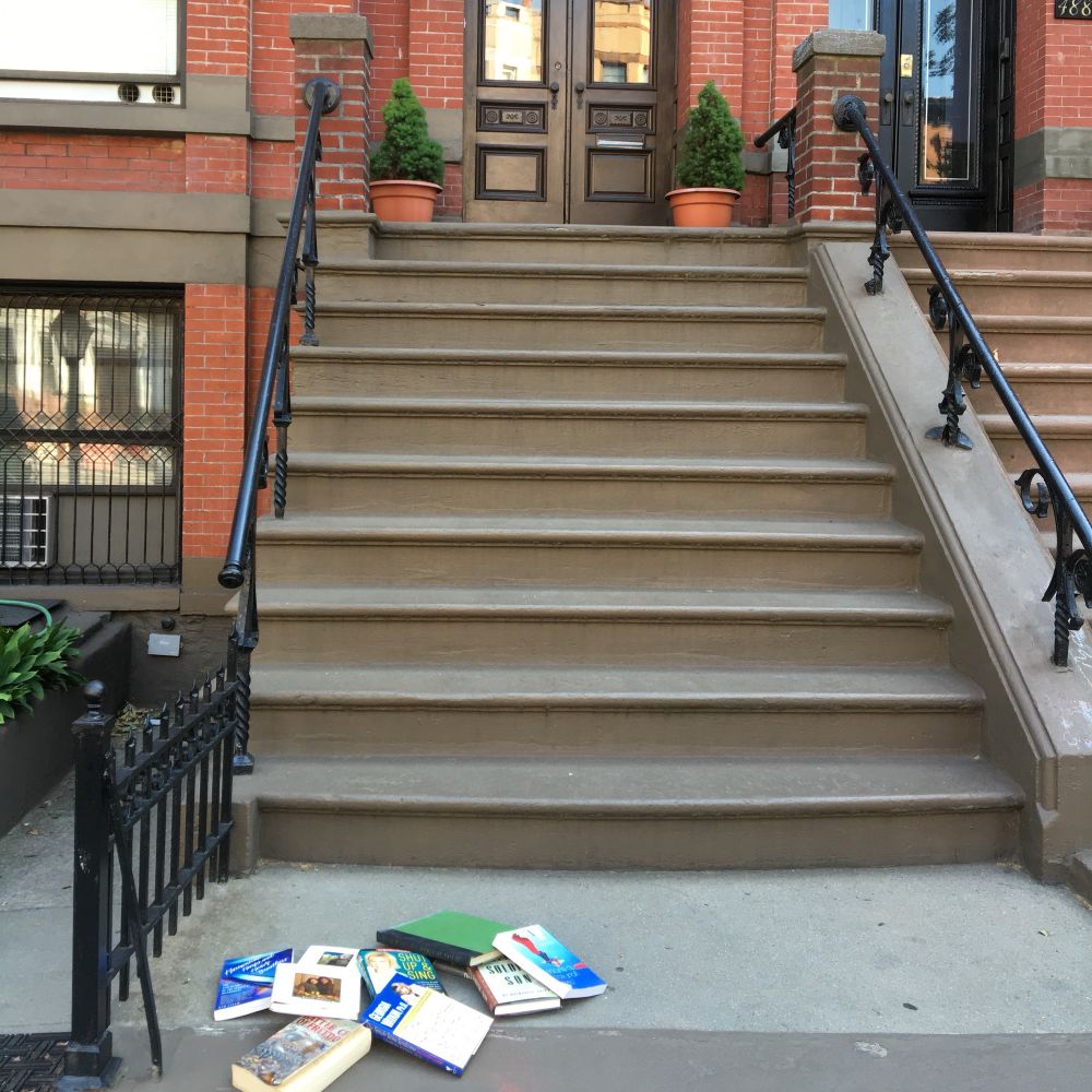 Brownstone building in New York with books on feminism dropped on the bottom step.