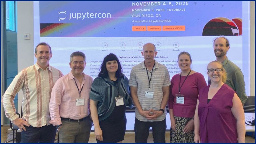 7 people standing in front of a projected slide featuring the “JupyterCon November 4-5, 2025” event