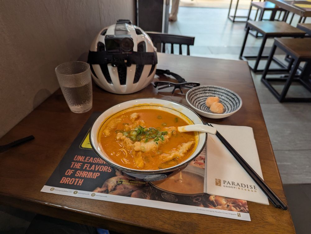 A picture of shrimp ramen and a bike helmet in a restaurant.