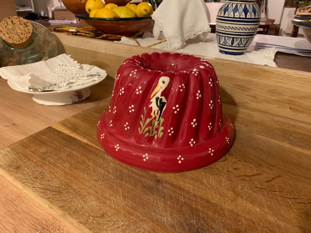 Moule à kougloff en terre cuite rouge parsemé de groupes de 4 points blancs. Une cigogne est également peinte dessus.