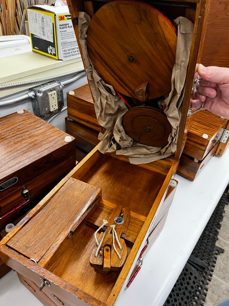 Image shows what it looks like inside of the case of a so-called book charkha. A charkha is a special, small, spinning wheel for cotton; specific to India and made famous by Mahatma Gandhi as part of his efforts to reclaim their independence from colonialism. 

A book charkha is a small, portable version of the spinning wheel in question that breaks down and stows in a box about the size of a large book (like a dictionary). 