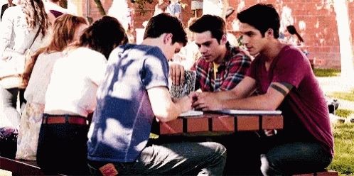 A group of kids sitting at a table talking. 