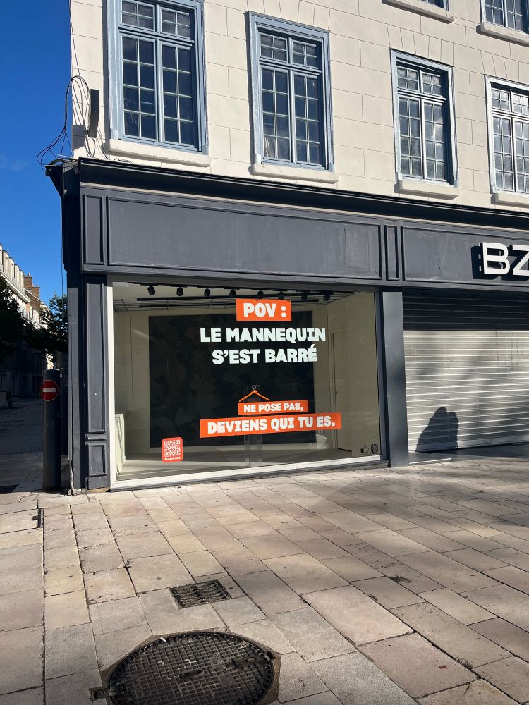 Devanture de boutique vide sur laquelle est écrit :
POV le mannequin s’est barré 
Ne pose pas : deviens qui tu es 