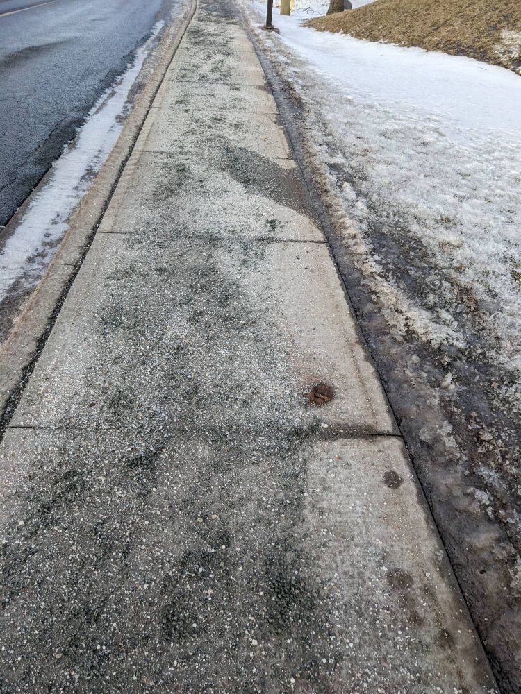 A clear sidewalk covered in salt and sand. Very passable.
