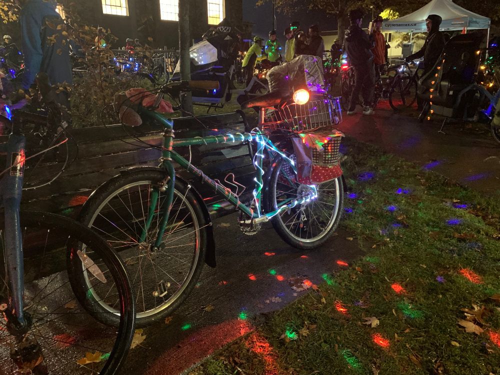 A bike with a lot of lights on its frame. There are lights all over the ground. 