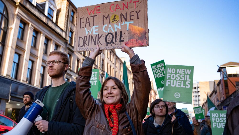 Councillor Holly Bruce holds up a placards that reads "We cant eat money. We cant drink oil."