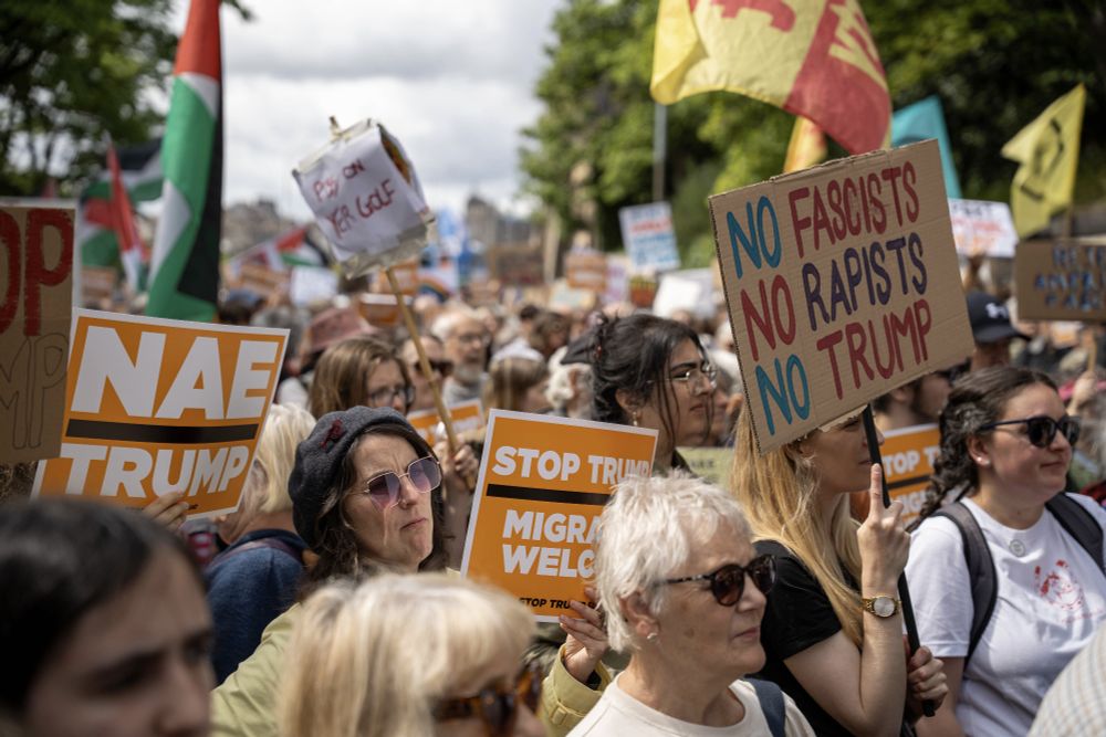 A large group of protestors against Trump in Edinburgh. Some are holding signs reading 'Nae Trump', 'Stop Trump, Welcome Immigrants' and 'No fascists, no rapists, no Trump'.