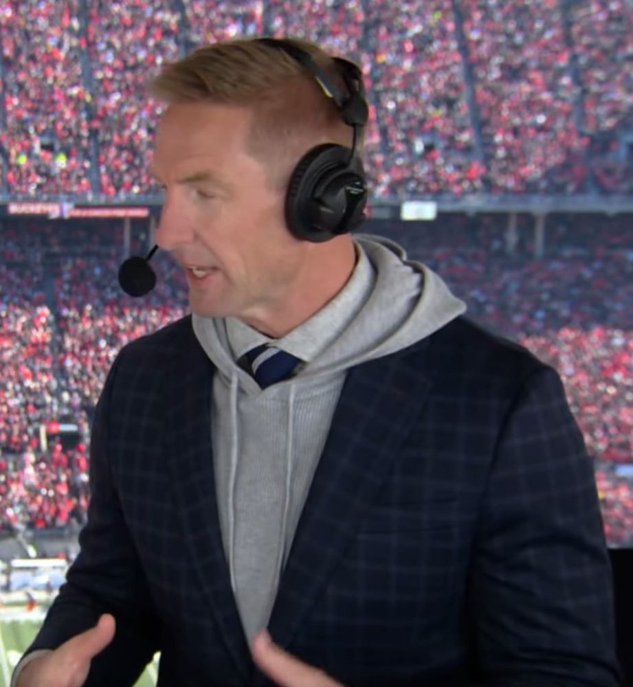 Joel Klatt wearing a light grey hoodie under a dark blue suit.