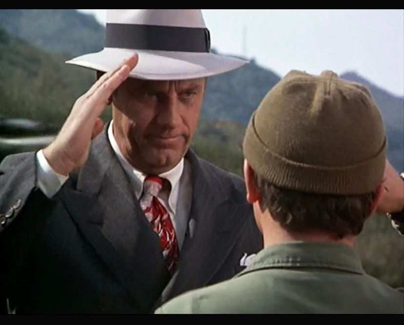 Henry Blake in a comedically bad suit/tie/fedora combo saluting Radar goodbye. 