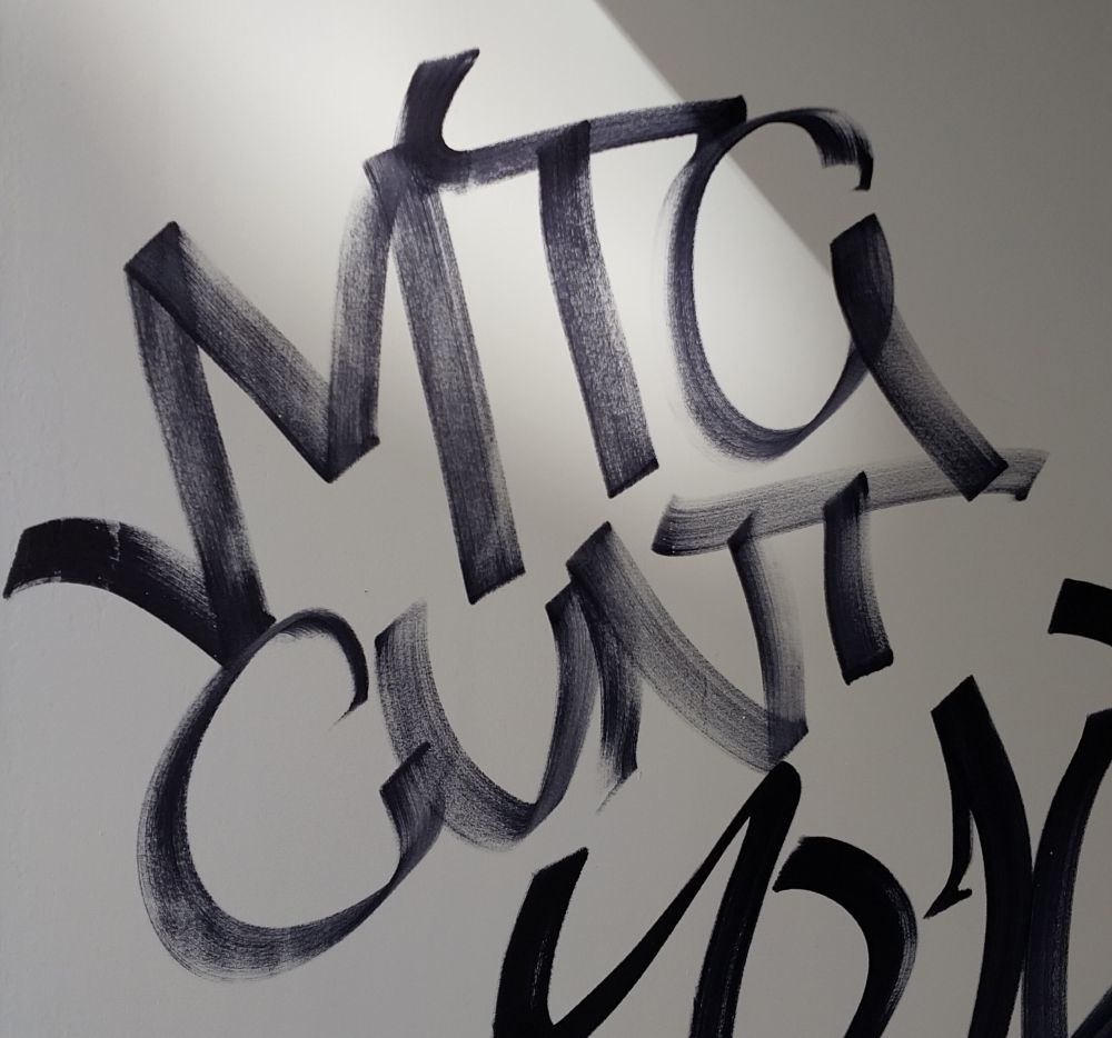 Graffiti, in black marker on white wall, reads "MTG CUNT"