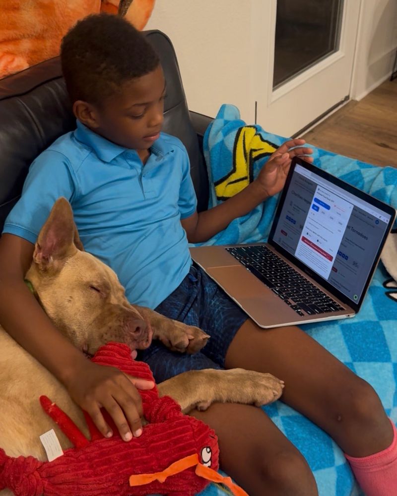 Cai the human sits on the couch as he explores the internet. Waylon is nestled into his lap without a worry in the world 
