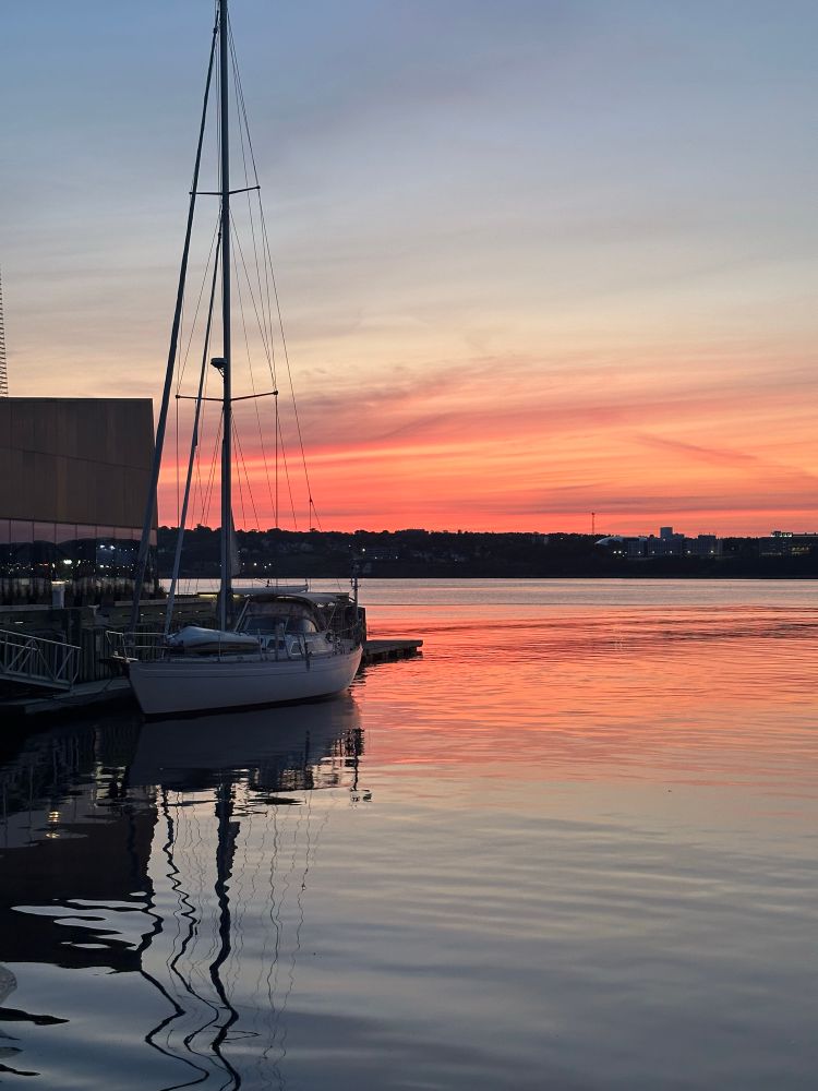 Sunrise over the harbour behind a sailboat. 