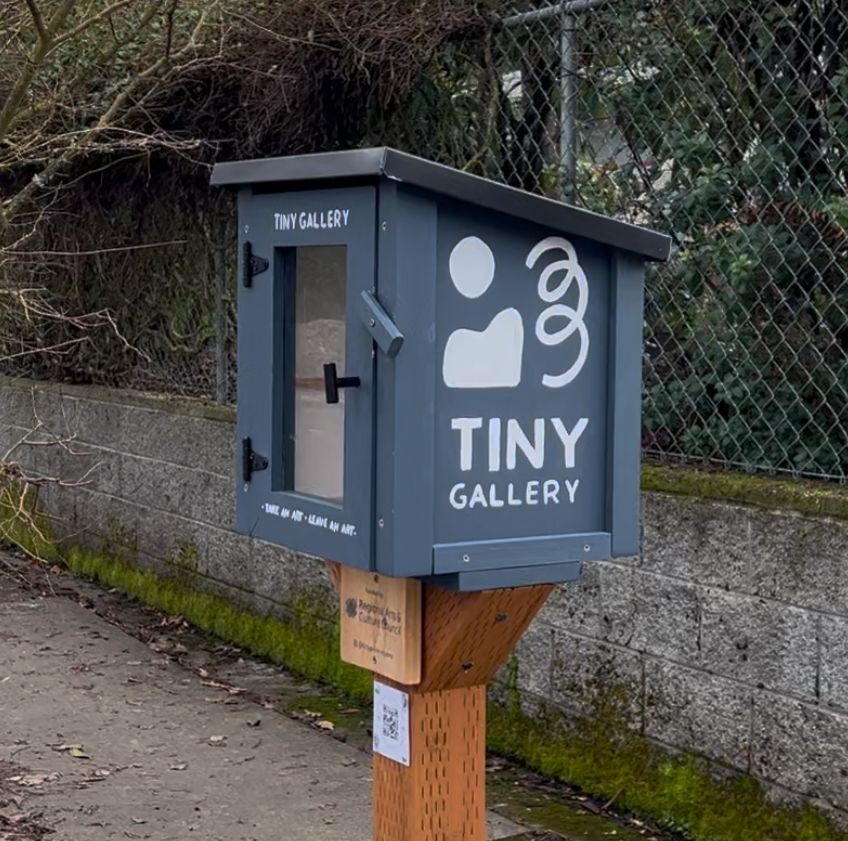 A small outside structure on a public sidewalk called Tiny Gallery that displays mini pieces of art. 