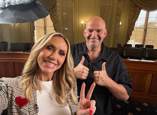 Lara Trump stands in front John Fetterman, in Fetterman’s Senate office.  Hypocritically Lara made the hand signal for a peace sign.  Fetterman stands behind her with a huge smile, hand signaling 2 thumbs ups
. 