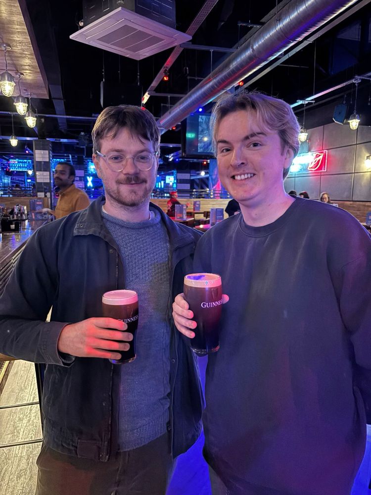 Two men posing with pints they borrowed
