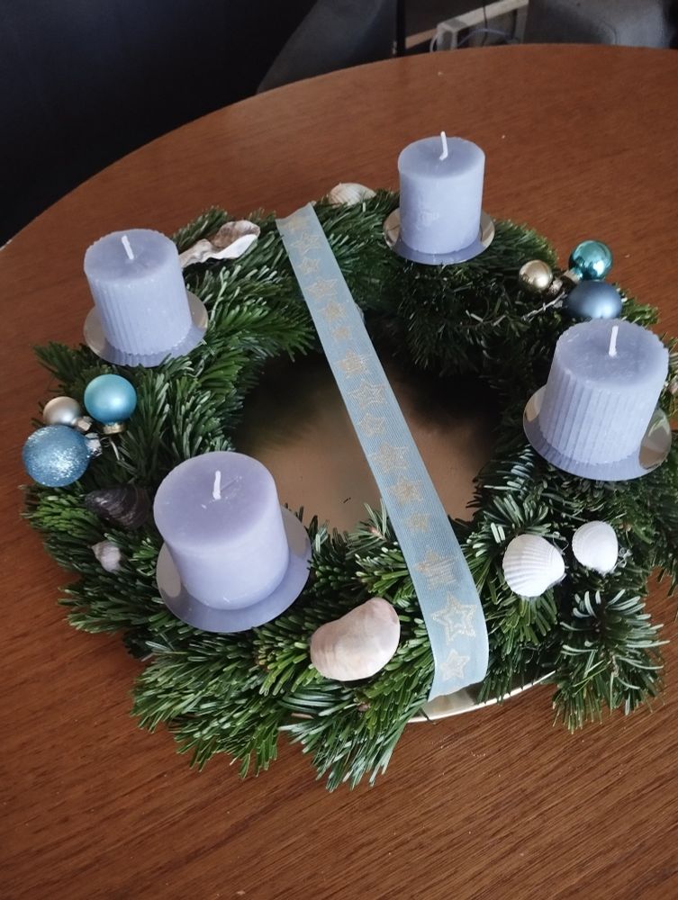 Selbstgebastelter Adventskranz. Blaue Kerzen, blaues Band mit leicht goldenen Sternen, 6 kleine Weihnachtskugel (2x3 in Blautönen und Gold), verschiedene Muscheln.
