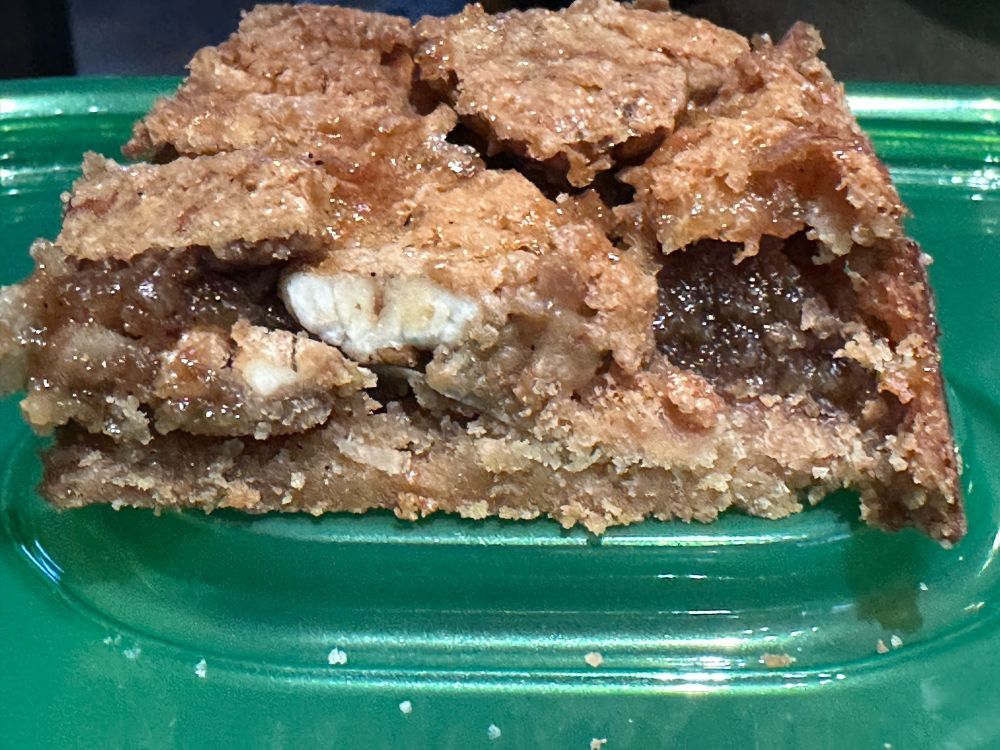 Brownish square of pecan pie bar cross section sitting on a green container lid