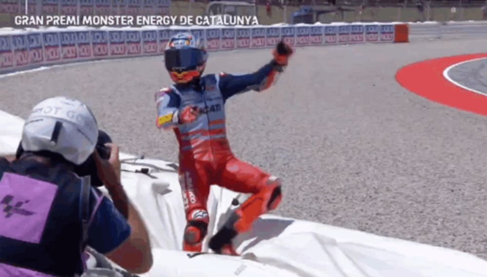 a man in a red and blue motorcycle suit is on a race track with the words gran premi monster energy de catalunya written above him