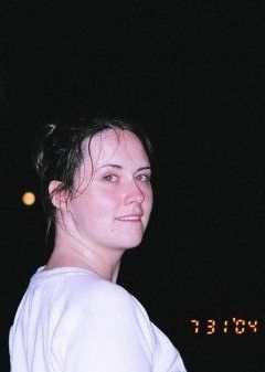 Photo of Elizabeth at 29 yrs old. She has her hair up in a ponytail, is wearing a white sweater, and is looking back over her shoulder at the photographer. The date of the photo is time stamped in the lower right corner: 7-31-04