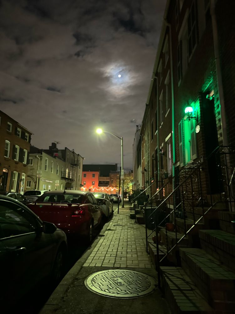 Moonlight shines down on a street of quintessential Baltimore row homes.