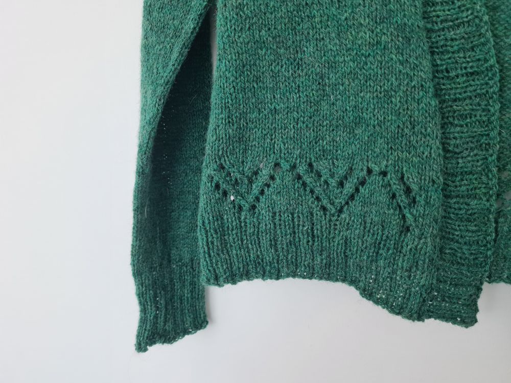Lace Pattern at the hem of a green handknitted cardigan. 