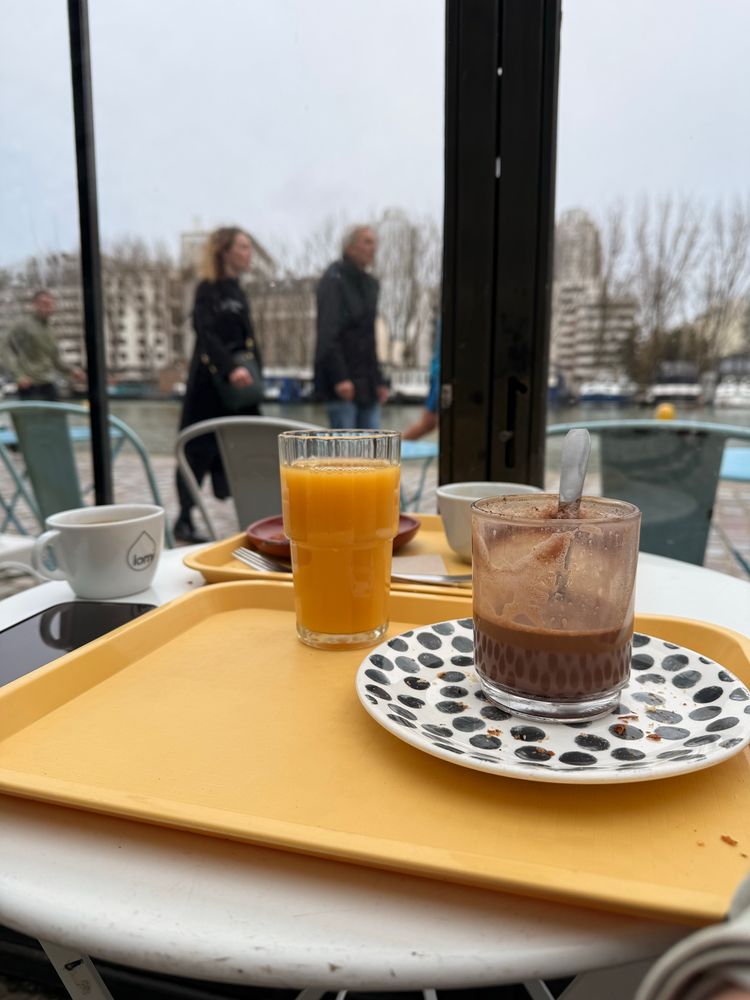 Quelques boissons sur une table derrière une verrière donnant sur le canal de l’Ourcq