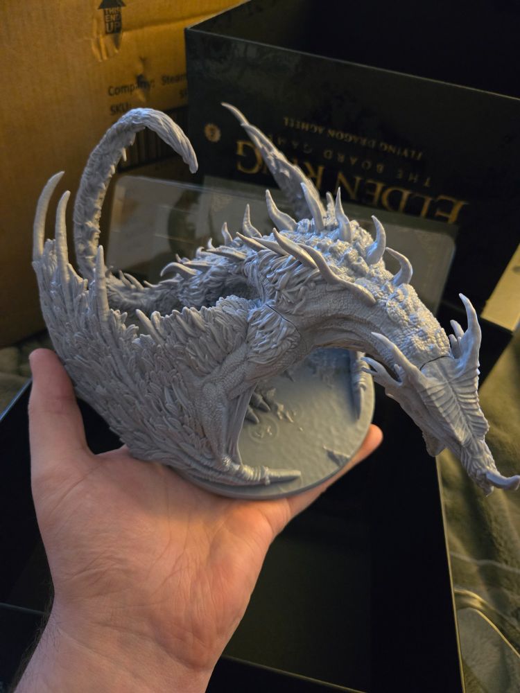 Large mini of Agheel, in grey, being held above open box.