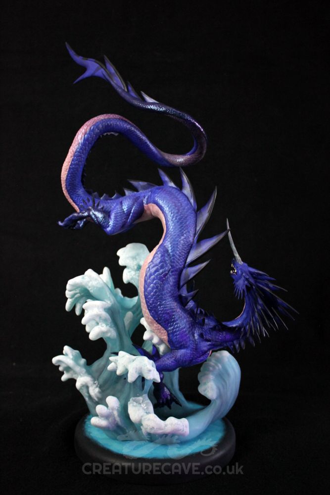 A sculpture of a blue and cream dragon, above a wave of water.