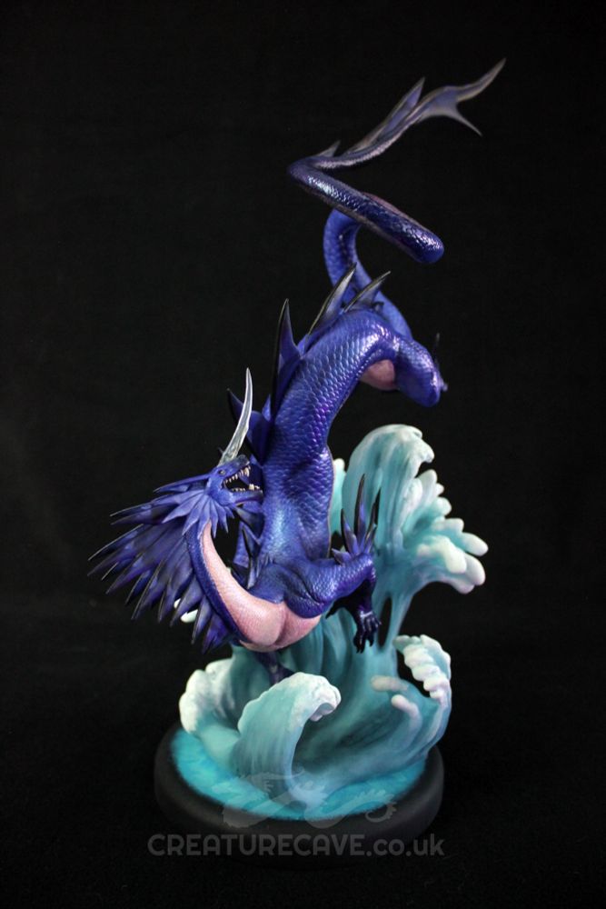 A sculpture of a blue and cream dragon, above a wave of water.