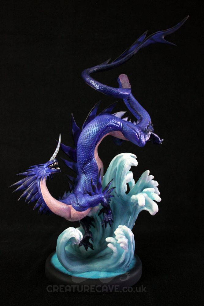A sculpture of a blue and cream dragon, above a wave of water.
