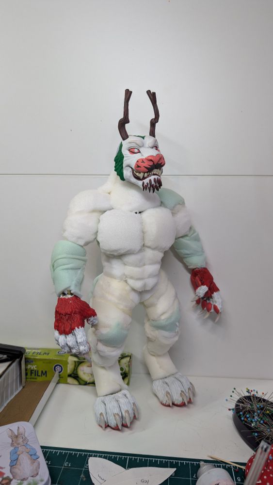 A puppet/character doll of a white and red lion like character. You can see white foam shaping the body, in a very muscular look.