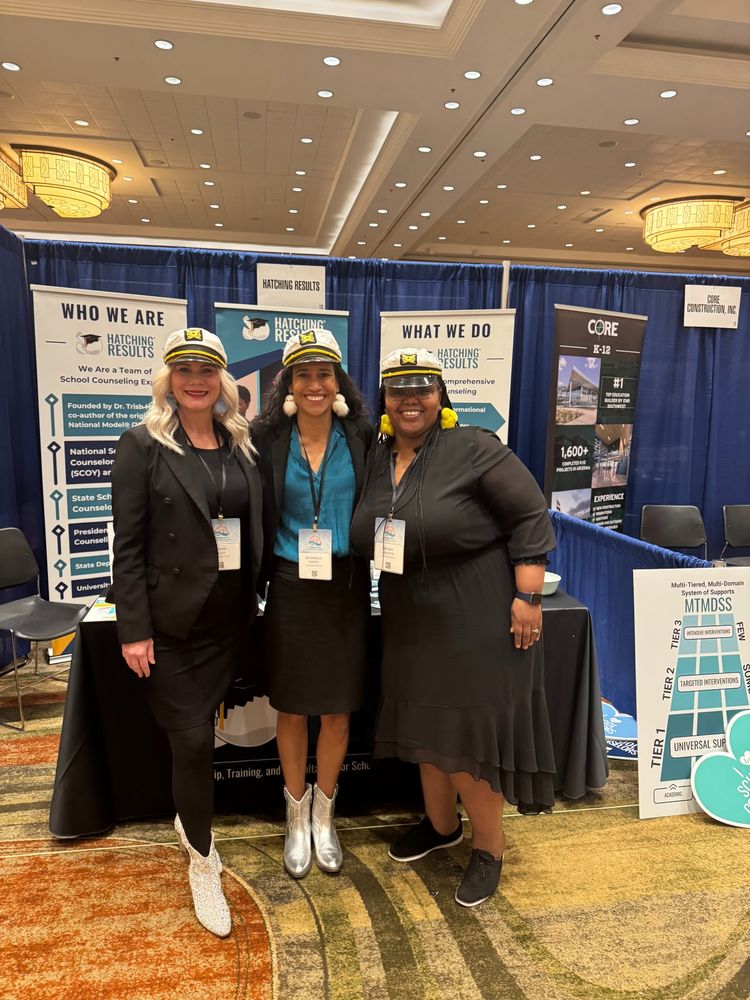 Our team standing in front of our booth in ship's captain hats, aligned with the conference theme of "Charting the course!"